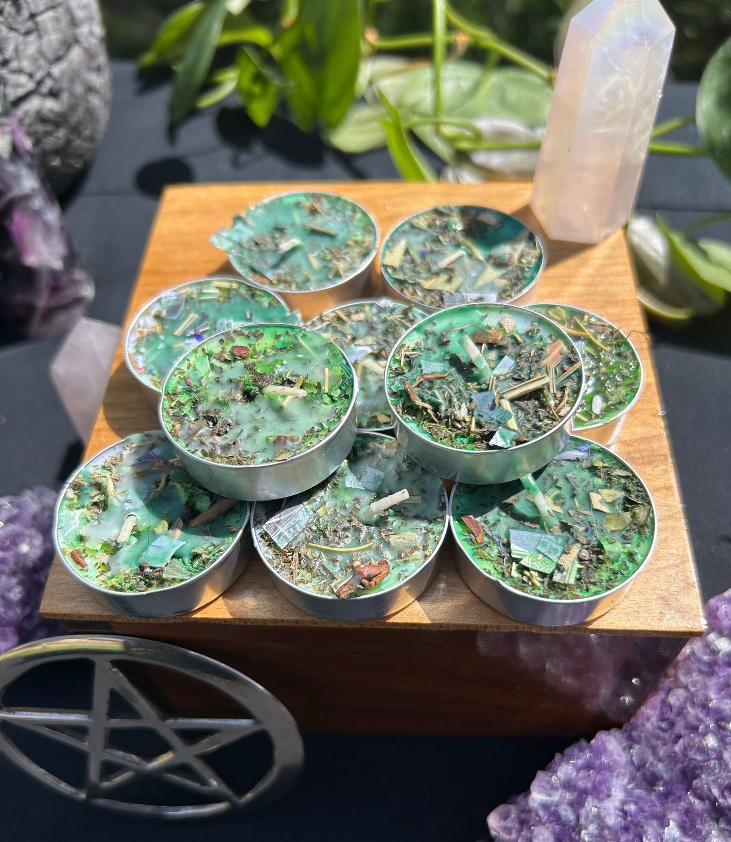 Set of small round containers with green and brown contents on a wooden board, surrounded by crystals and plants.