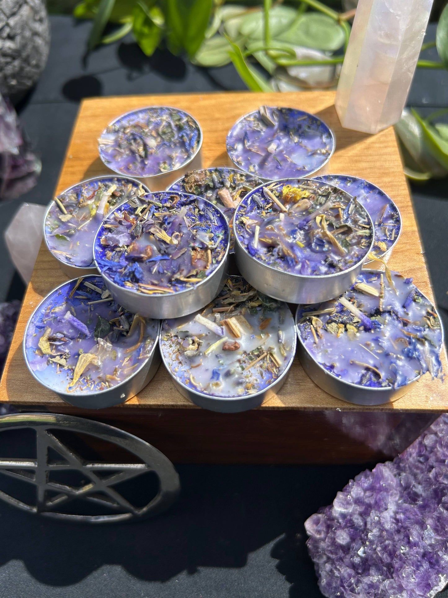 Set of purple and gold decorative items on a wooden stand with plants in the background
