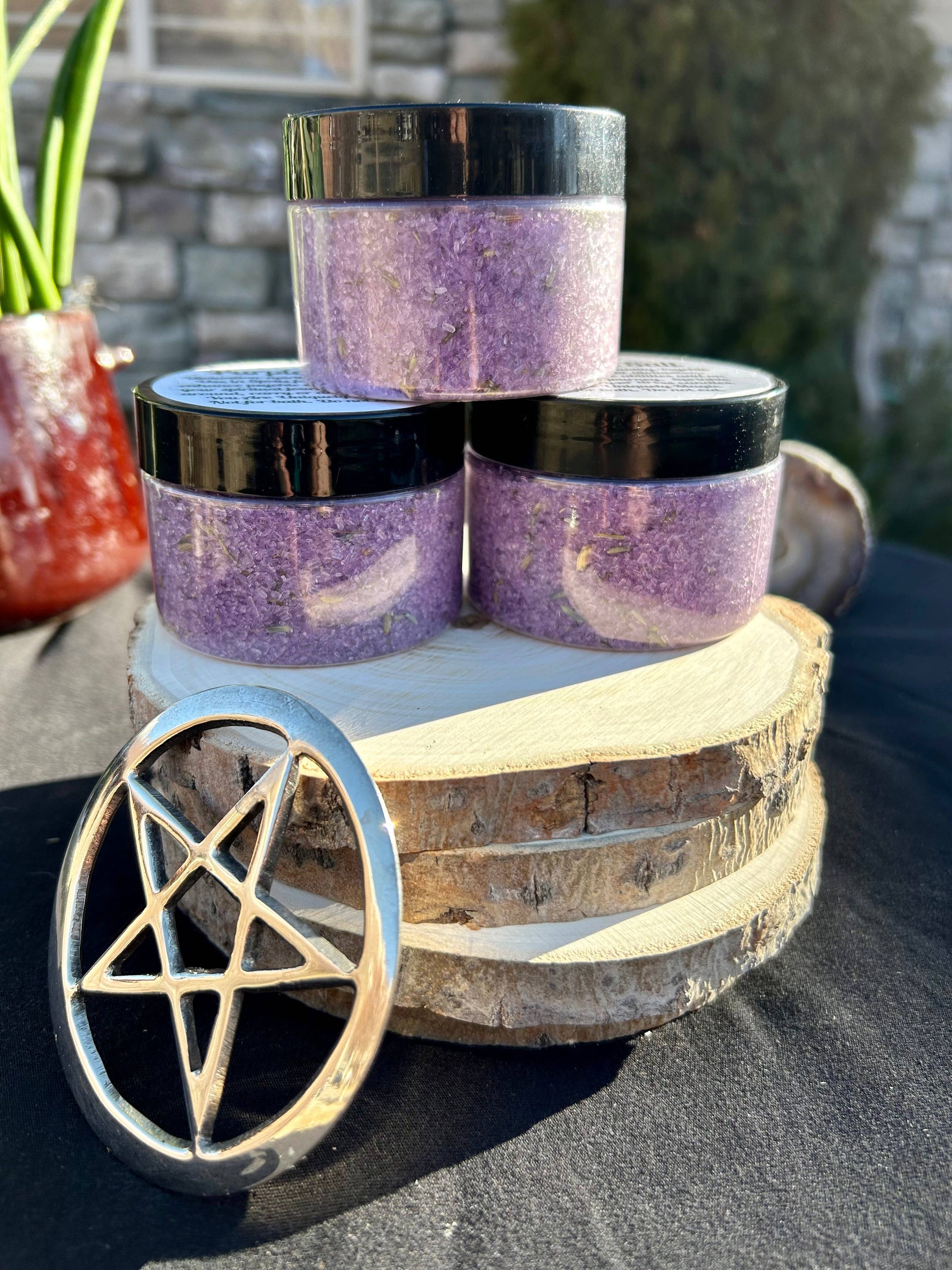 Three jars of purple powder on a wooden stand with a pentagram symbol, outdoor setting.