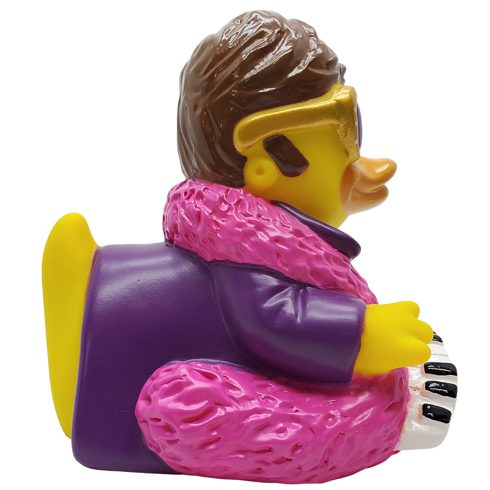 Toy figure of a person with a purple coat and pink scarf playing a keyboard on a white background