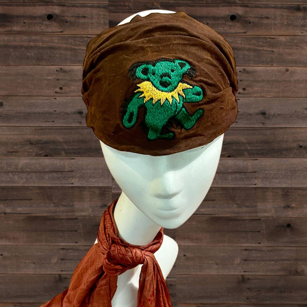 Brown velvet turban with embroidered bear design on a wooden background