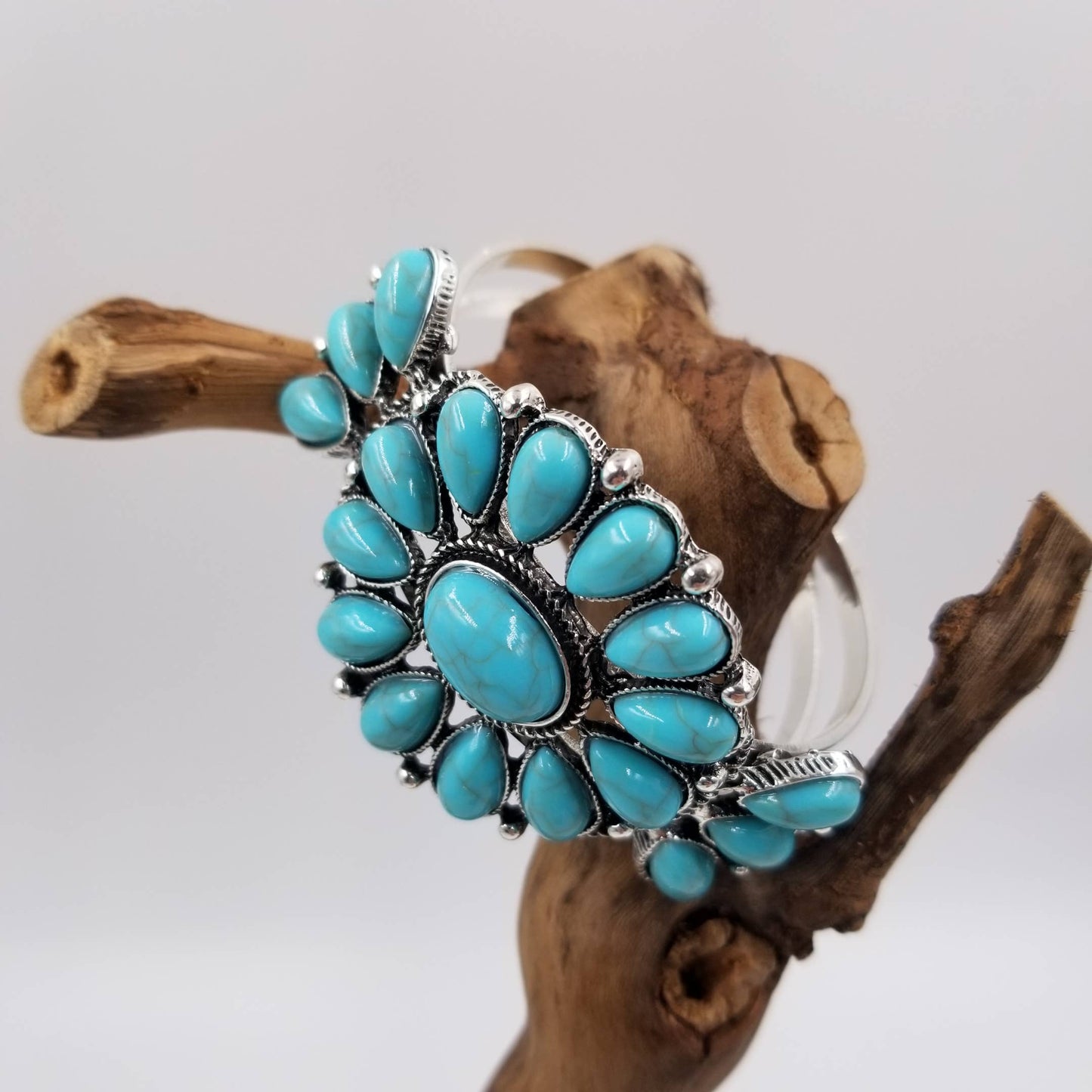 Turquoise stone bracelet on a wooden branch with a white background