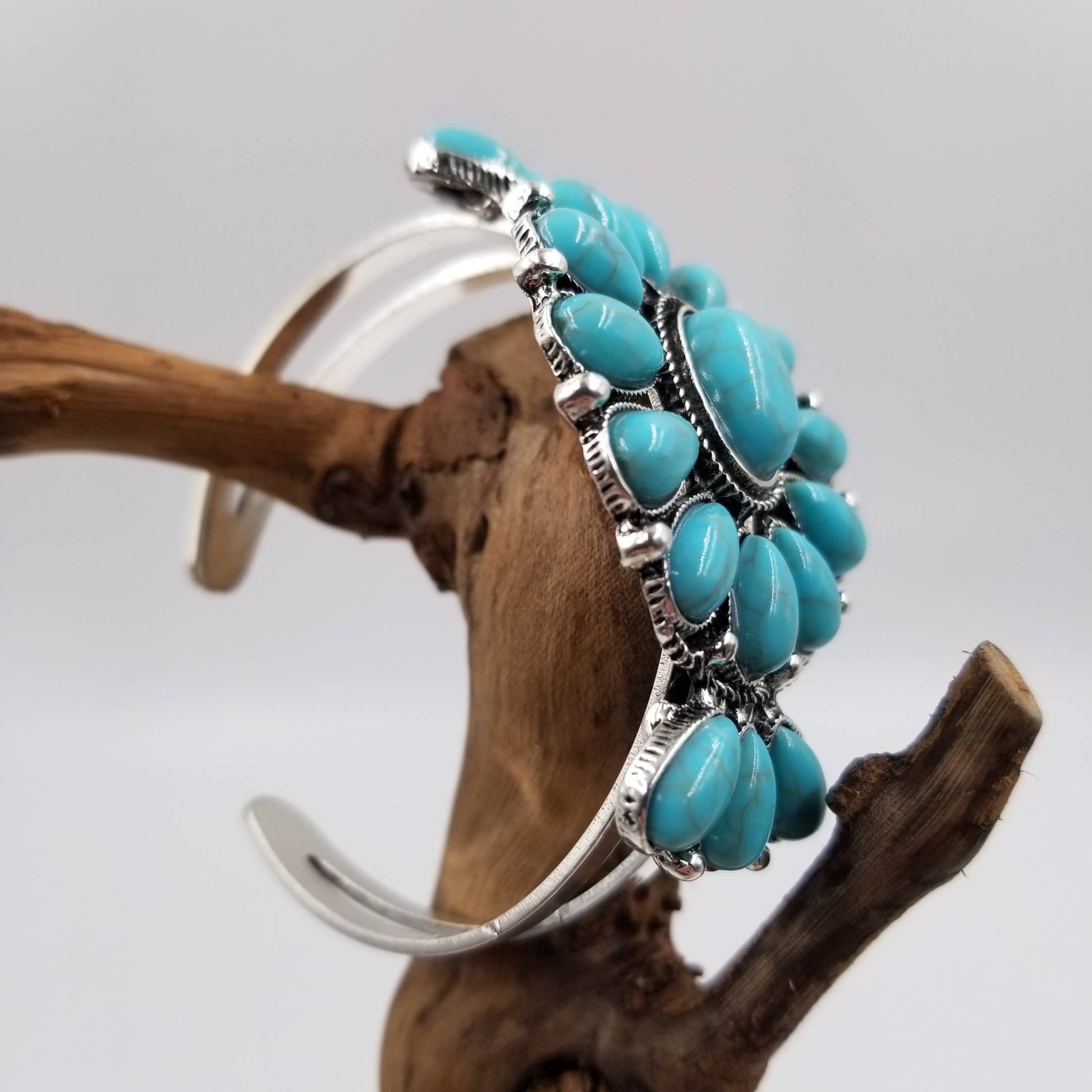 Turquoise beaded bracelet on a branch with a gray background