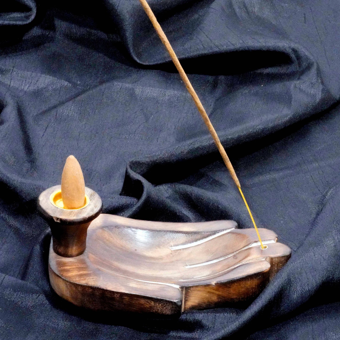 Incense burner with a single incense stick on a dark fabric background