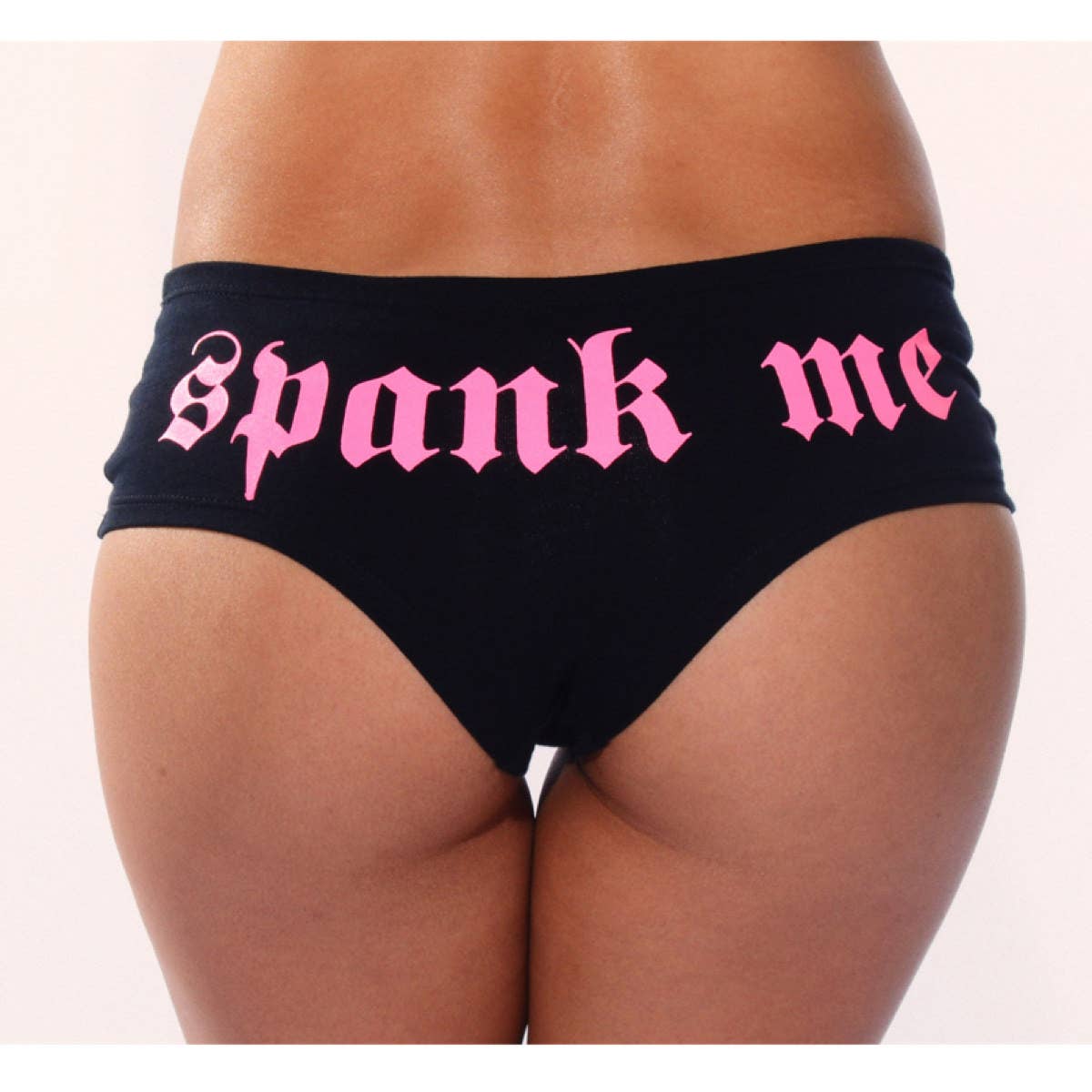 Black underwear with pink 'spank me' text on a white background