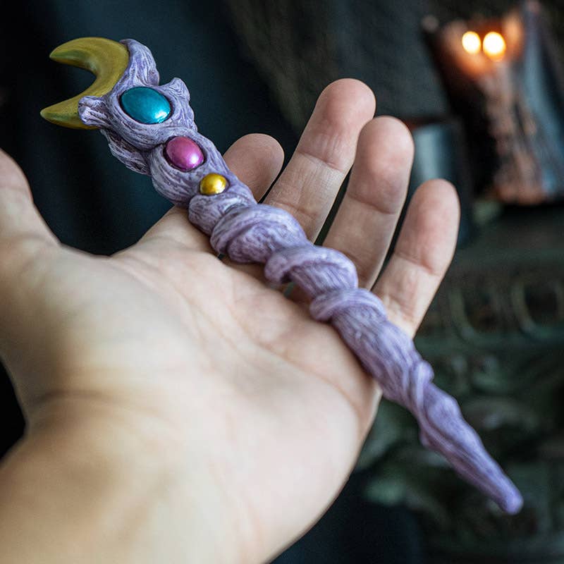 Hand holding a decorative wand with colorful beads against a blurred background