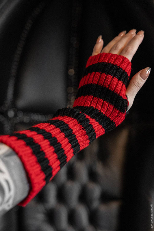 Red and black striped fingerless gloves worn by a person with a blurred background