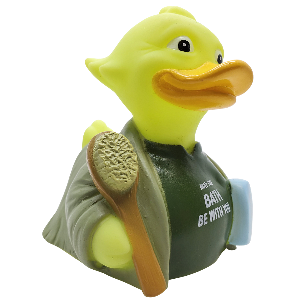 Yellow rubber duck wearing a green shirt with text and holding a brown brush on a white background