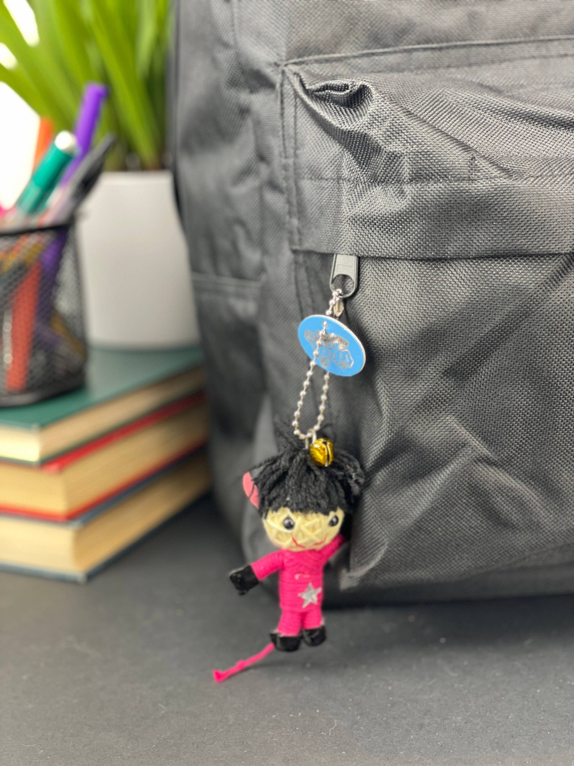 Keychain attached to a gray bag with books and stationery items in the background