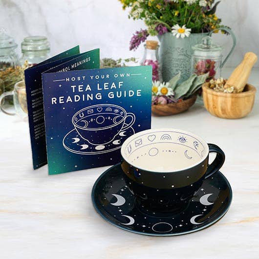 Tea cup and saucer set with 'Host Your Own Tea Leaf Reading Guide' book on a table.