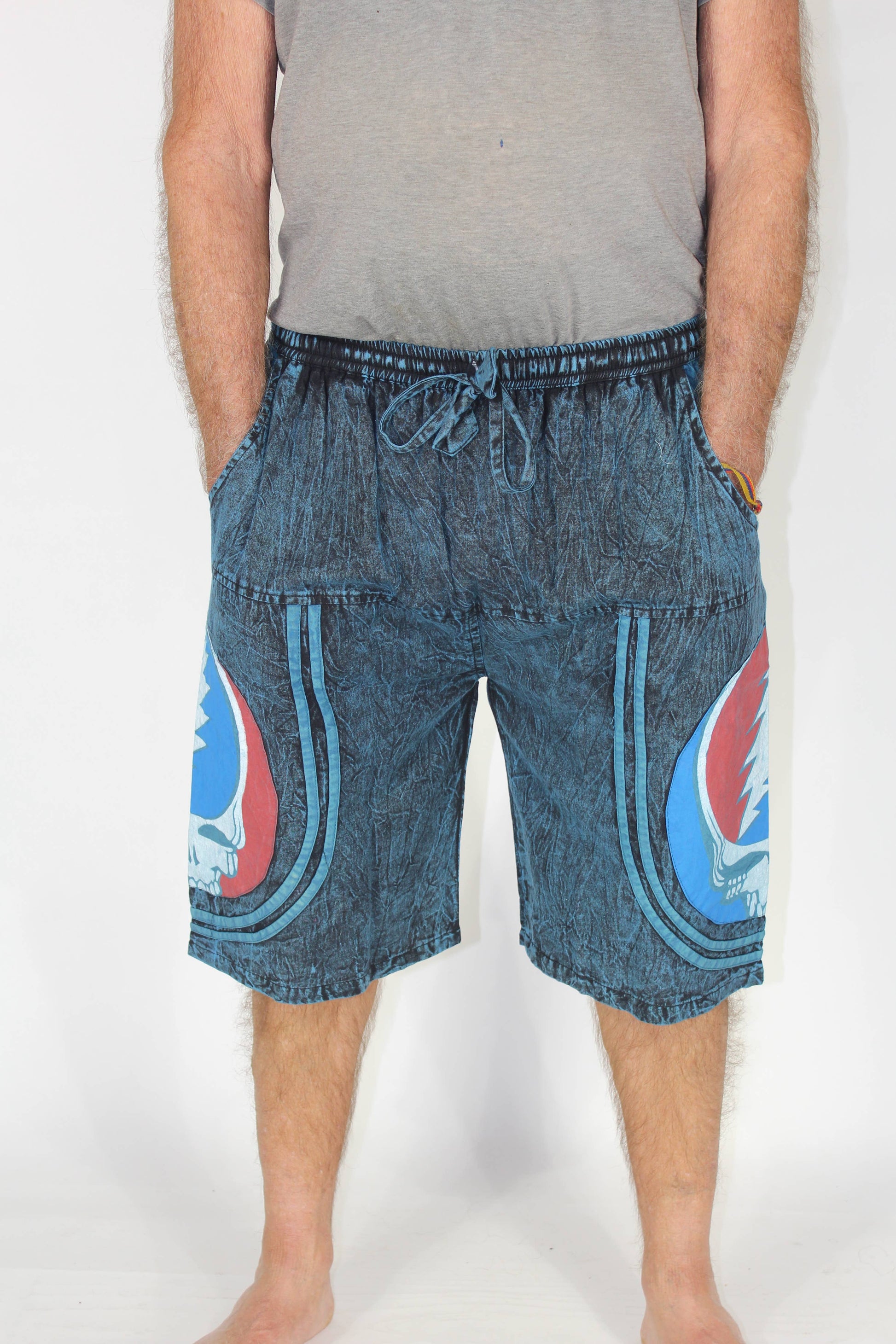 Person wearing blue denim shorts with graphic designs on a white background