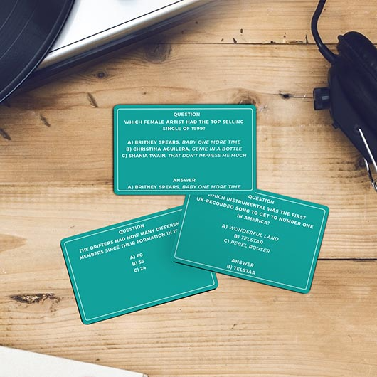 Three green question cards on a wooden surface with a car key and cup holder in the background.