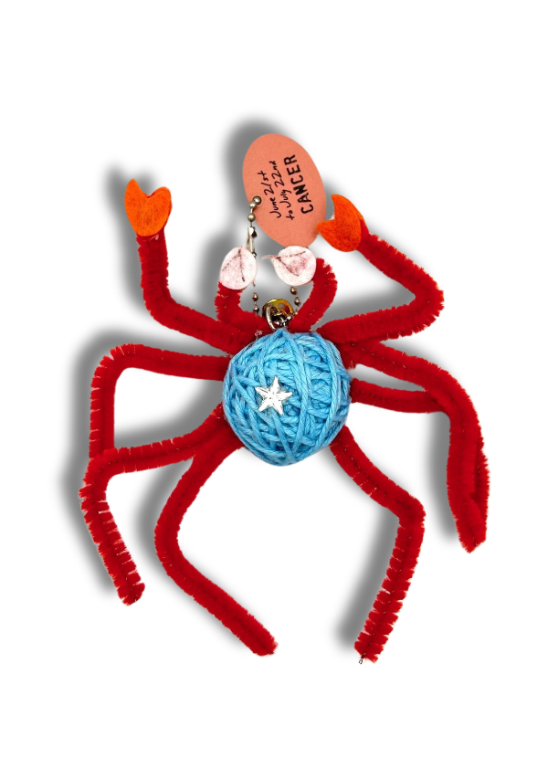 Red spider-shaped key chain with a blue ball and star on a white background