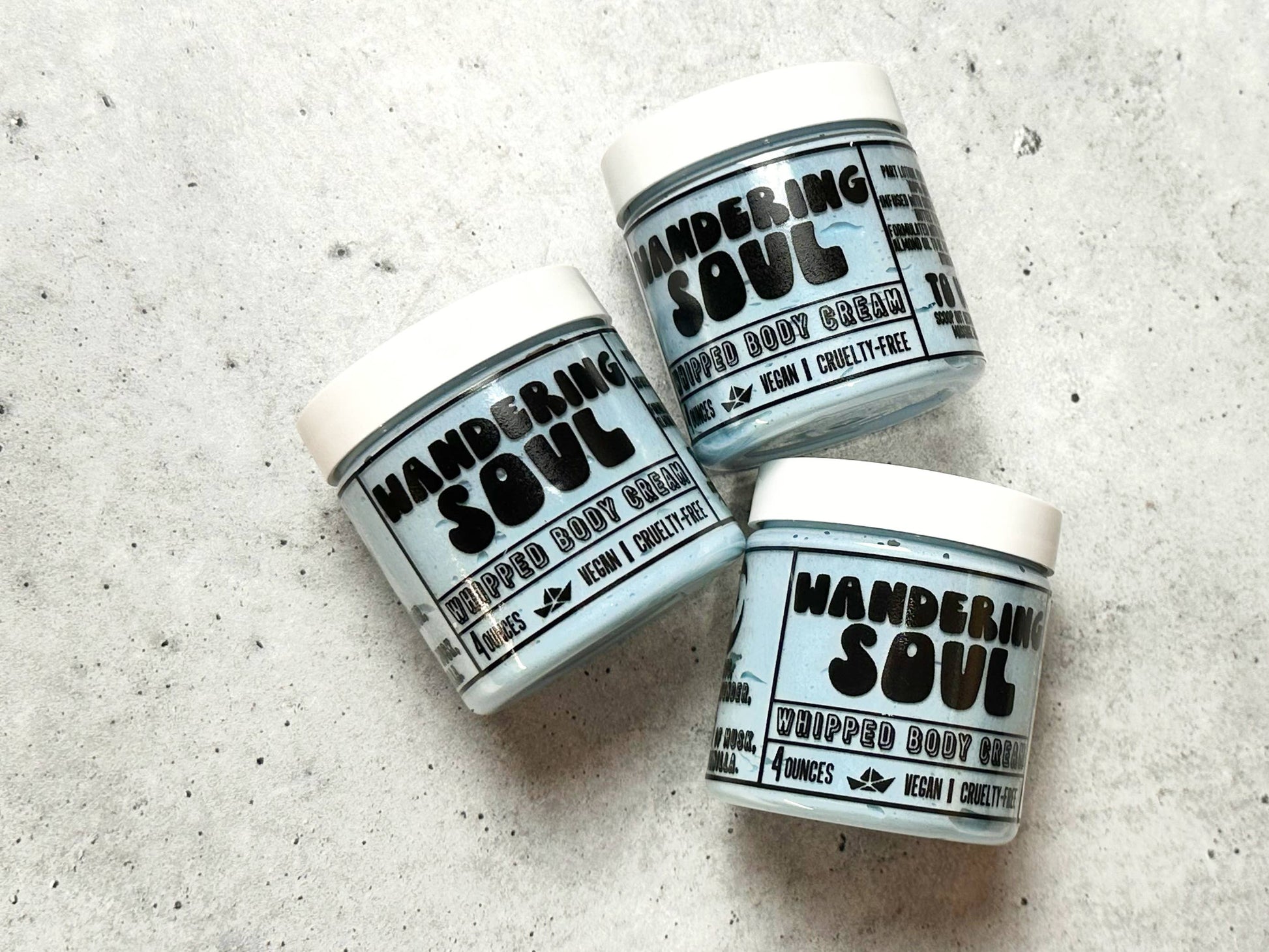 Three jars of 'Wandering Soul' whipped body cream on a textured surface