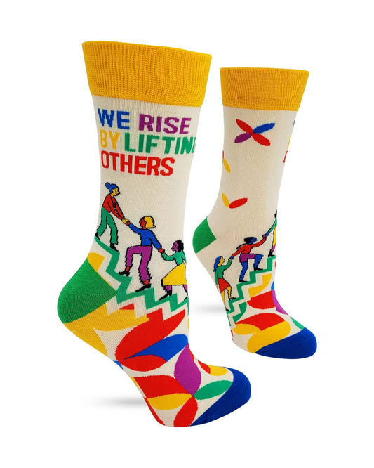 Colorful socks with a design of people holding hands and the text 'We Rise by Lifting Others' on a white background.