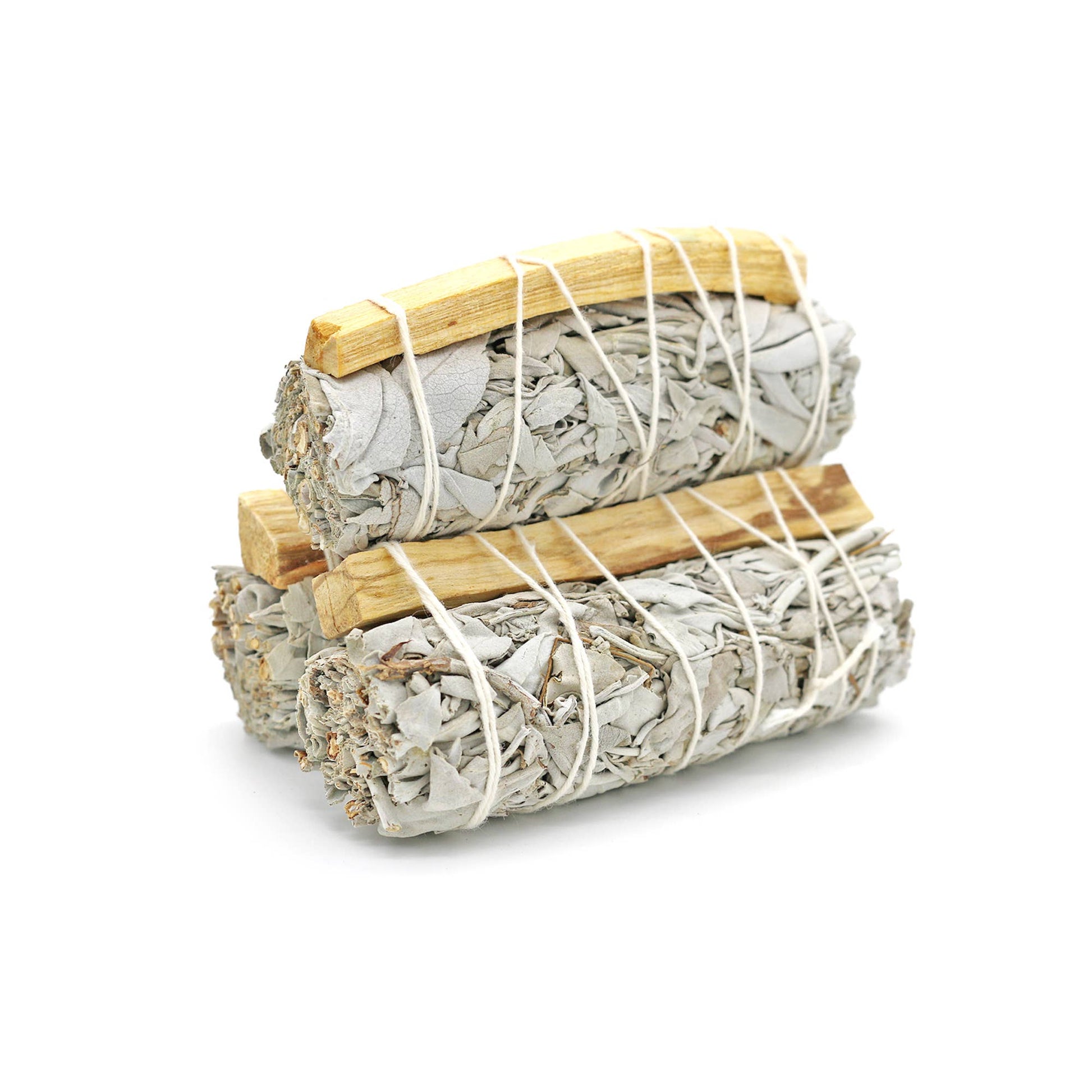Two bundles of sage smudge sticks tied with twine on a white background