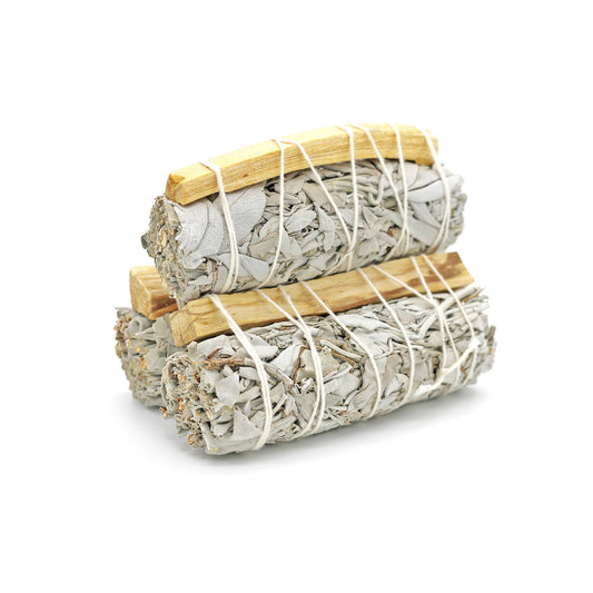Two bundles of sage smudge sticks tied with twine on a white background