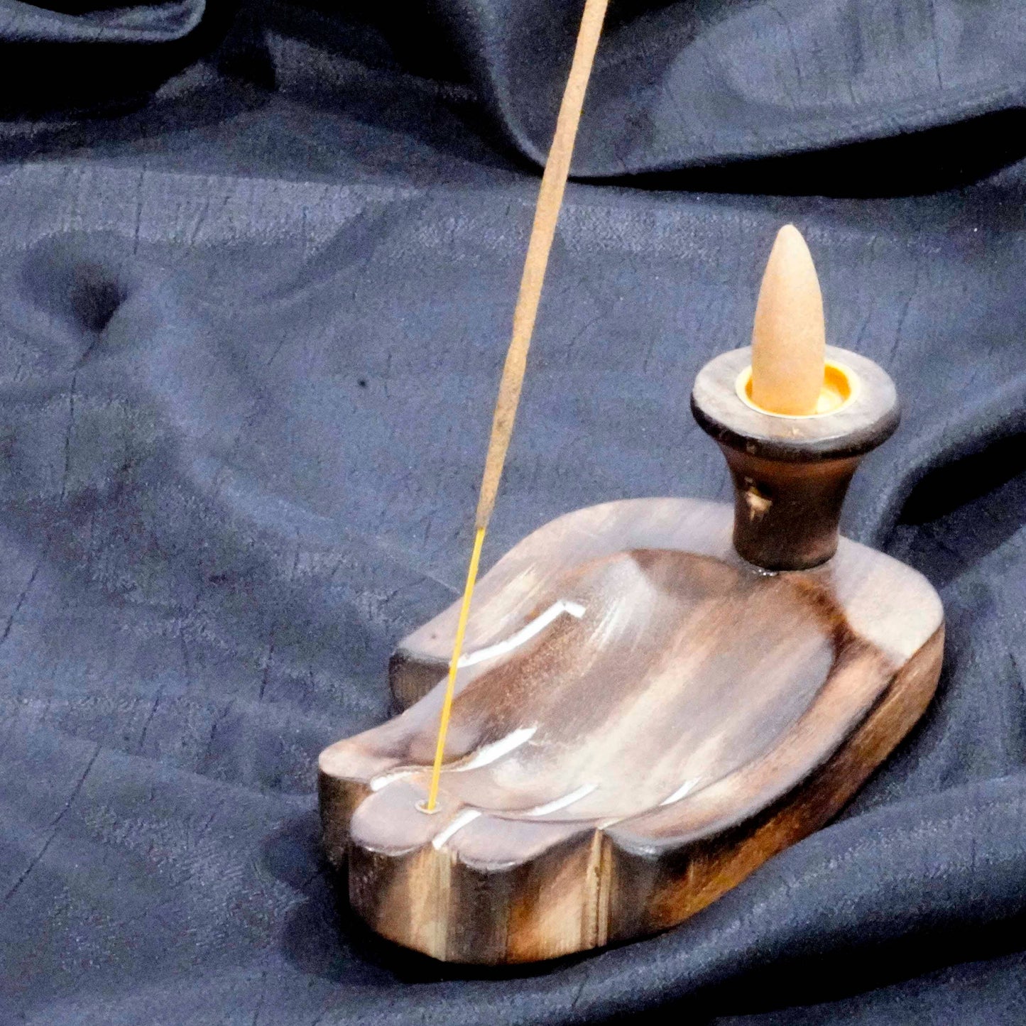 Incense burner with a stick of incense on a blue fabric background