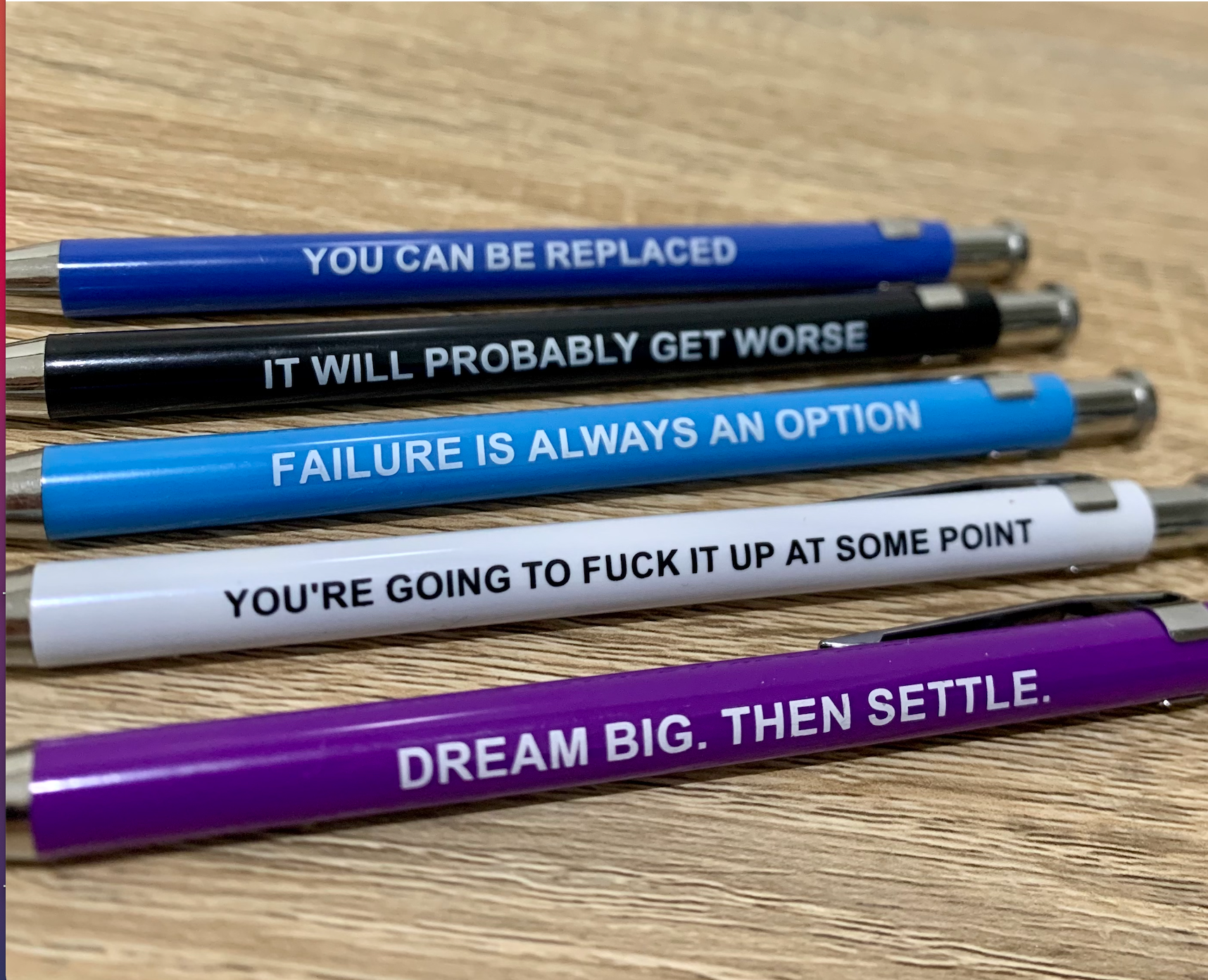 Set of pens with motivational quotes on a wooden surface