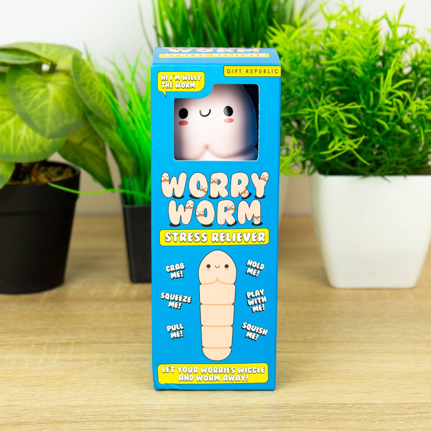 Worry Worm stress reliever packaging on a wooden surface with plants in the background