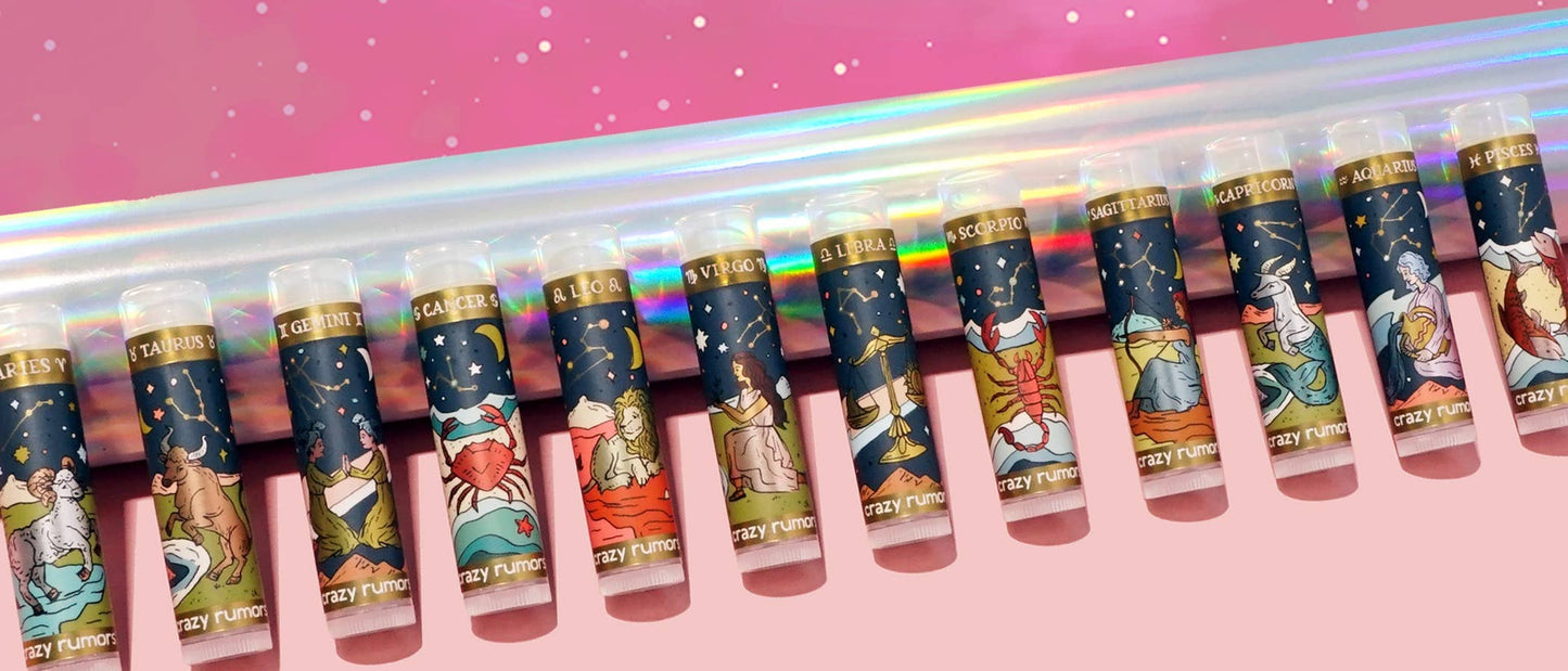 Row of colorful lip balm tubes with various designs on a pink background